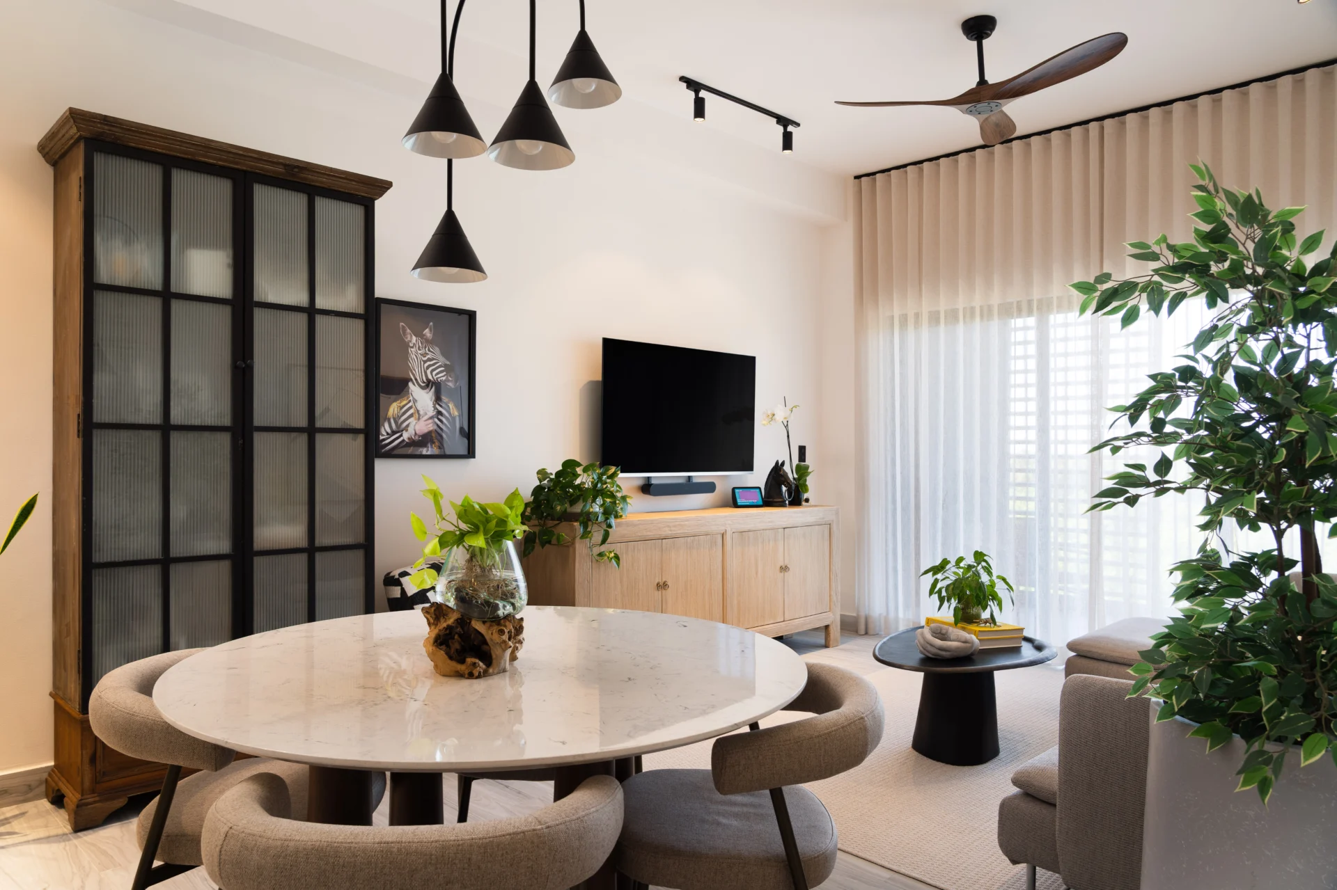 Sala moderna en Punta Cana con planta, mesa redonda de mármol y ventilador de techo de madera